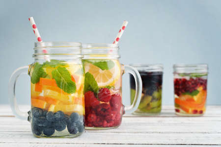 Detox drinks with fresh fruits and berries in glass jars on blue backgroundの写真素材