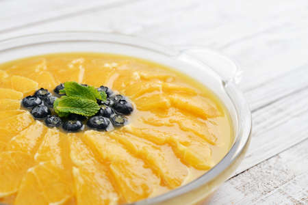 Pie with orange slices and blueberry in jelly on wooden background closeupの写真素材