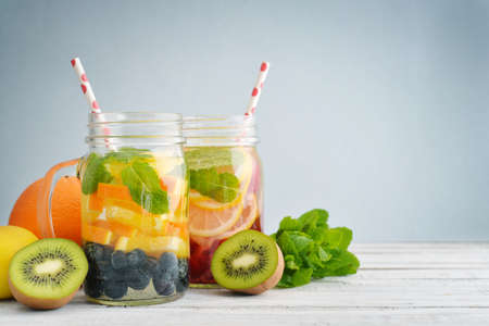 Detox drinks with fresh fruits and berries in glass jars on wooden backgroundの写真素材