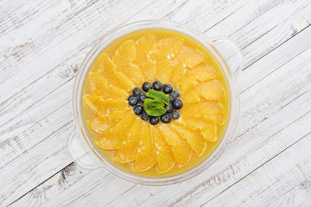 Pie with orange slices and blueberry in jelly on wooden background top viewの写真素材