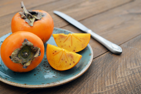 Ripe sweet persimmons on wooden table closeupの写真素材