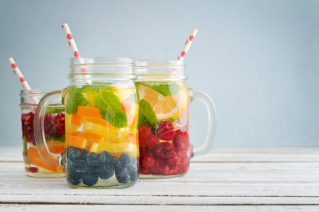 Detox drinks with fresh fruits and berries in glass jars on wooden backgroundの写真素材
