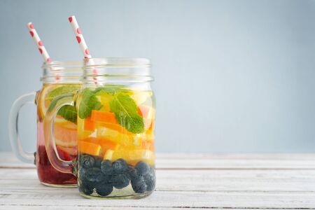 Detox drinks with fresh fruits and berries in glass jars on wooden backgroundの写真素材