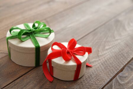 Round gift boxes with red and green ribbons on wooden backgroundの写真素材