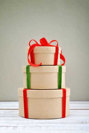 Round gift boxes with red and green ribbons on green backgroundの写真素材