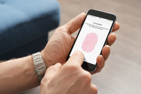 Kiev, Ukraine - March 06, 2016: Man using touch ID scanner of fingerprints on  iPhones 6, developed by Apple corporation. Allows users to unblock the smartphone and to make purchases.のeditorial素材