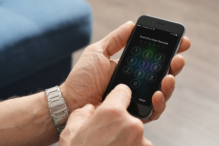Kiev, Ukraine - March 06, 2016: A man hand holding the Apple iPhone 6 and enter passcode. The cellular phone is produced by Apple Computer, Inc.のeditorial素材