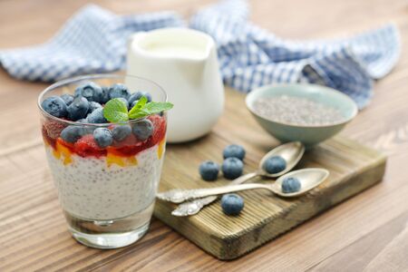 Pudding with chia seeds, yogurt and fresh berries in glass on wooden backgroundの写真素材
