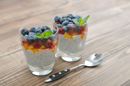 Pudding with chia seeds, yogurt and fresh berries in glass on wooden backgroundの写真素材