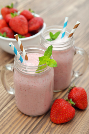 Fruit smoothies with strawberry and banana in jar with handle on wooden backgroundの写真素材