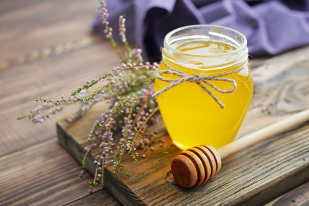 Herbal honey in jar with fresh heather on wooden backgroundの写真素材