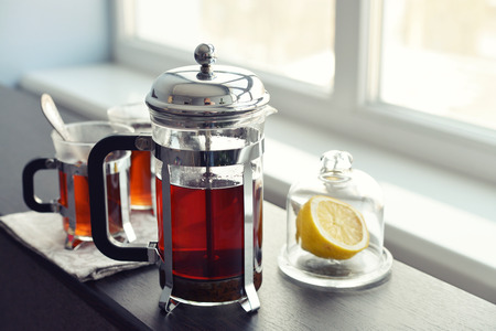 Cups of tea  with french press and lemon on sofa in living room closeup.の写真素材