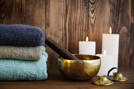 Tibetan handcrafted singing bowls with towels and candles on wooden backgroundの写真素材