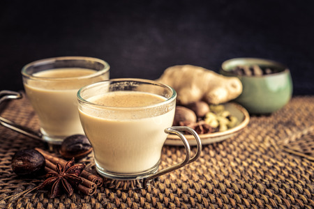 Traditional indian drink - masala chai tea (milk tea) with spices on rattan trayの写真素材