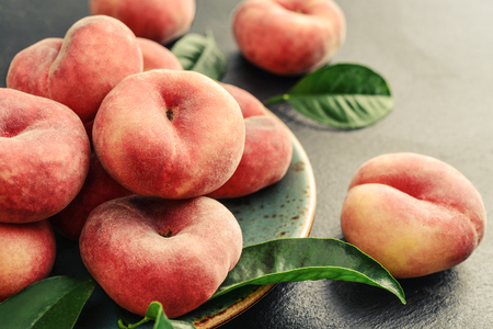 Ripe peaches on blue plate on black background closeupの写真素材