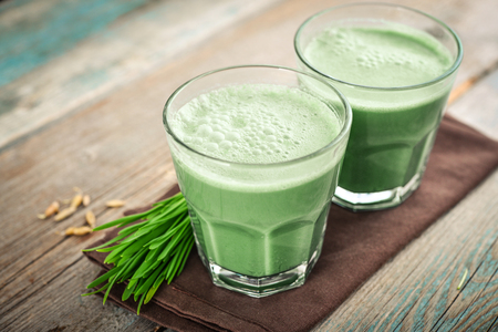 Two green barley grass shots with blades of young barley on a wooden backgroundの写真素材
