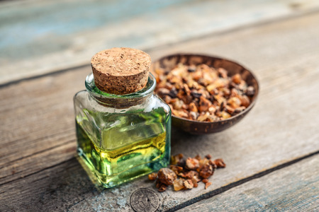 A bottle of myrrh essential oil with myrrh resin on a wooden backgroundの写真素材