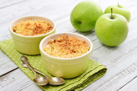 Apple crumble in small baking dish with fresh apples on wooden backgroundの写真素材