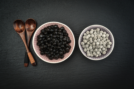 Boiled and Raw Tapioca Pearls in plates on black slate background. For Bubble tea concepts.の写真素材