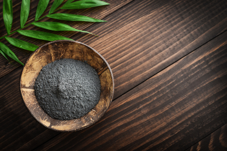 Black cosmetic clay in coconut bowl on wooden background closeupの写真素材