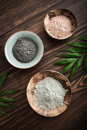 Different cosmetic clay in coconut bowl on wooden background top viewの写真素材