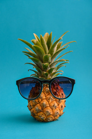 Fashion hipster pineapple fruit with sunglasses on blue backgroundの写真素材