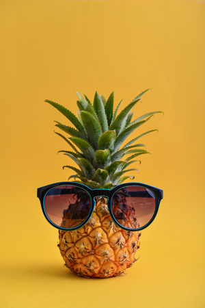 Fashion hipster pineapple fruit with sunglasses on yellow backgroundの写真素材