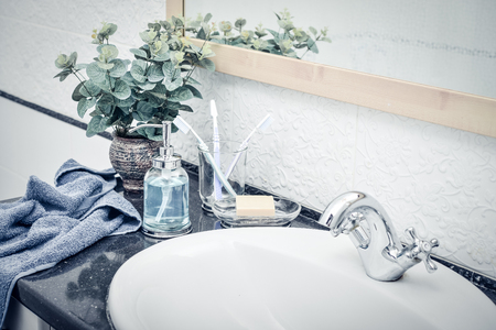 Vintage mixer tap in the bathroom with glass liquid soap dispenser, tooth brushes and towels closeupの写真素材