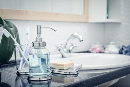 Bathroom set with glass liquid soap dispenser, toothbrushes, towels and soap in the bathroomの写真素材