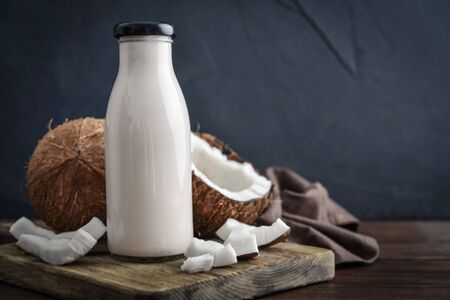 Coconut vegan milk non dairy in bottle with broken coconut on black backgroundの写真素材
