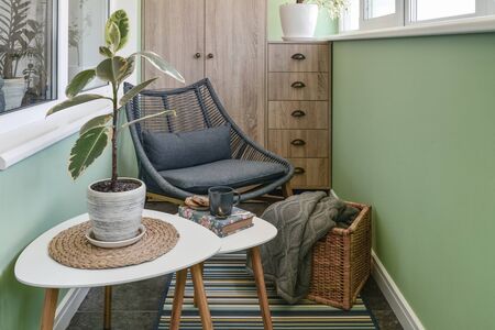 Interior of cozy balcony with green walls, sitting area with rug, armchair and two coffee tablesの写真素材