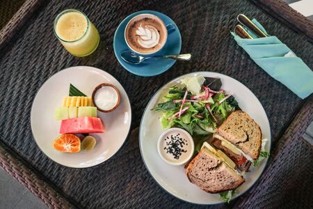 Sandwich, salad and bread basket with butter, jam and coffee on table, top view. Breakfast concept.の写真素材