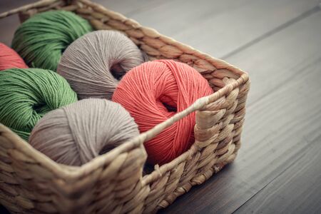 Colored yarn balls in rustic wicker basket on blue couch closeupの写真素材