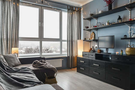 Light cozy  appartment with panoramic windows,  brown sofa and blue walls at winter timeの写真素材