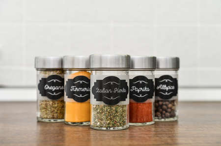 Glass jars with different spices in row on kitchen worktop closeupの写真素材