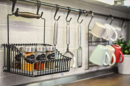 Glass jars with different spices in wire basket on kitchen worktop closeupの写真素材