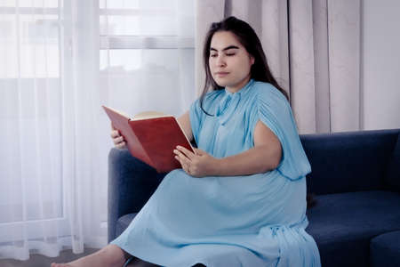 woman in turquoise dress sitting on sofa