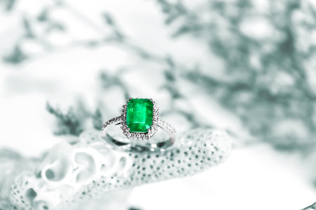 beautiful ring made of gold with precious stones emerald and diamonds on a black background close-up. High quality photoの写真素材