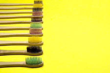Bright bamboo eco toothbrushes on yellow background. Selective focus.の写真素材