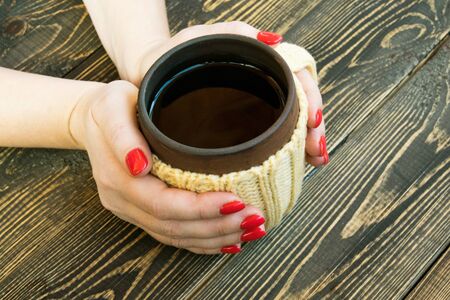 Cap of tea in female hands on wooden backgroundの写真素材
