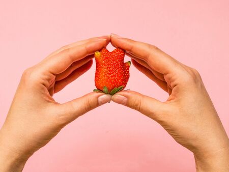 Ugly food: unusual strawberry in a woman hands.の写真素材
