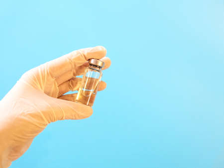 Bottle with vaccine in hand in medical gloves