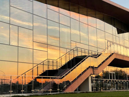 A sunset sky reflected in the glass wall of a building with a staircaseの写真素材