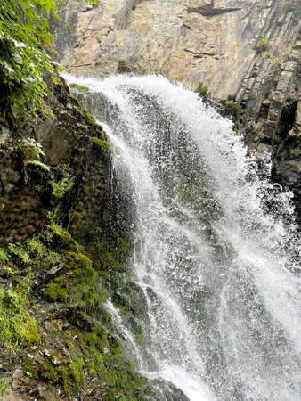 Mountain waterfall flowing among rocks in a narrow gorgeの写真素材