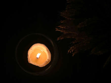 A candle in a glass lampshade is burning on a table near a dry spikelets. Christmas festive table...