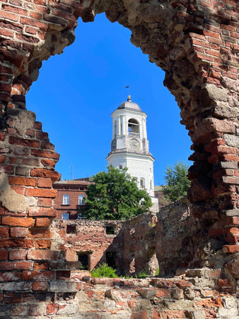 Clock tower on a sunny day. View through a destroyed brick wall. Vyborg, Leningrad region, Russiaの写真素材