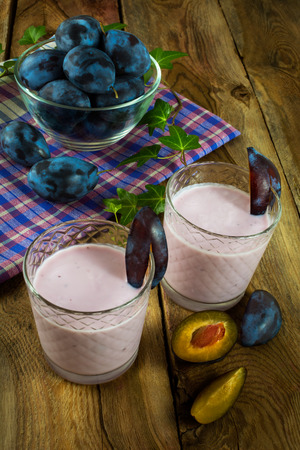 Fresh fruit, plum smoothies, prune yogurt, diet healthy drink in a glass on a dark wooden background, vertical. Selective focusの写真素材