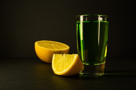 Absinthe and lime on black background. Alcohol drink. Green alcohol drink