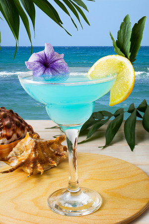 Blue Hawaiian cocktail on the tropical beach. Iced blue cosmopolitan cocktail. Blue Lagoon margarita martini cocktail. Summer beach alcohol drinkの写真素材