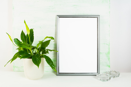 Silver frame mockup with flower pot and candles. Portrait or poster white frame mockup. Empty white...